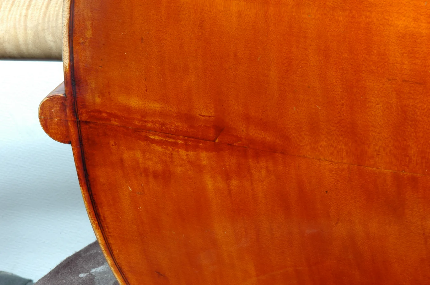 The flamed back of a bass with re-touched varnish across a repaired seam.